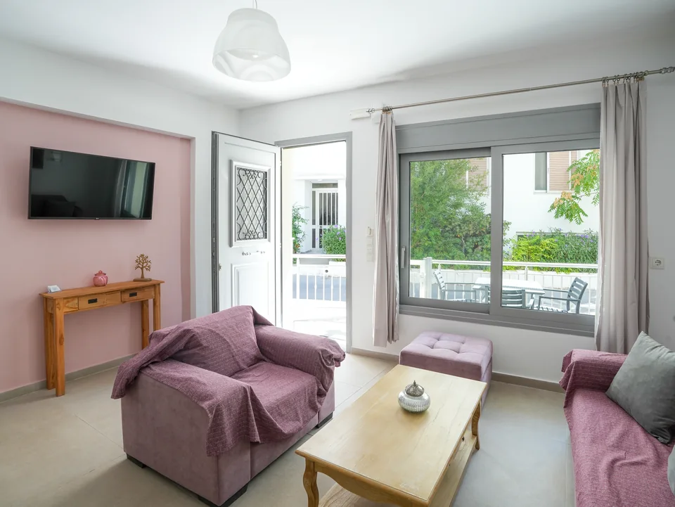 Sitting room with television, armchairs and doors to the garden