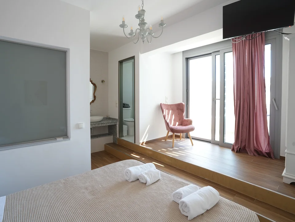 Double bedroom with balcony doors, armchair and folded towels