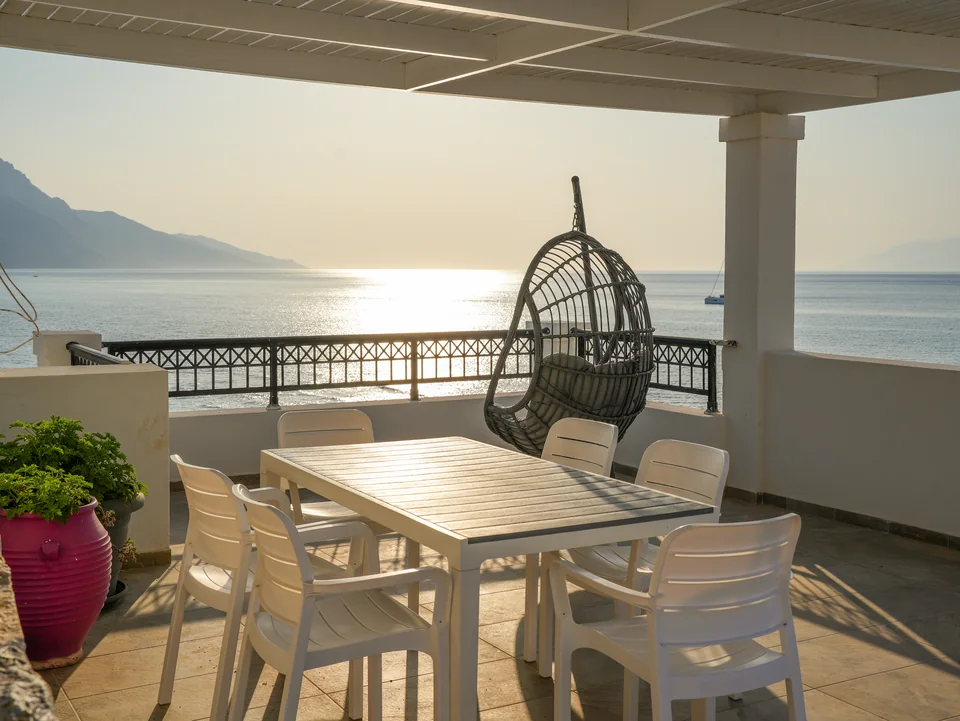 Roof terrace at Ostria View with dining table, hanging chair and open sea view