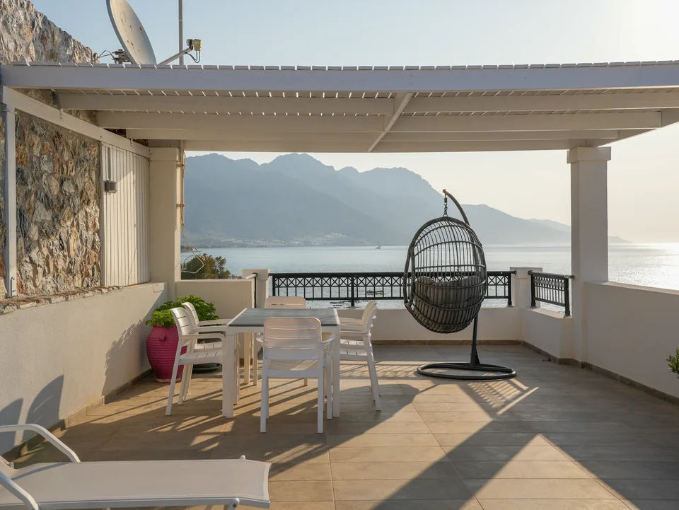 Shaded roof terrace with a hanging egg chair looking out over the bay