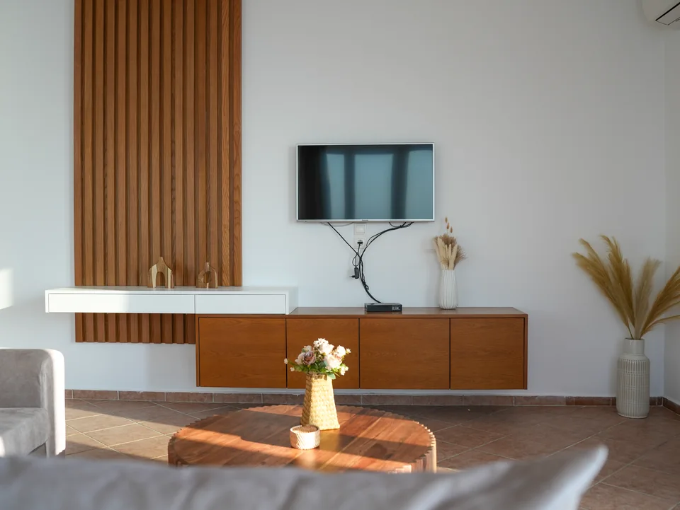 Wall-mounted television above a wooden sideboard in the living area