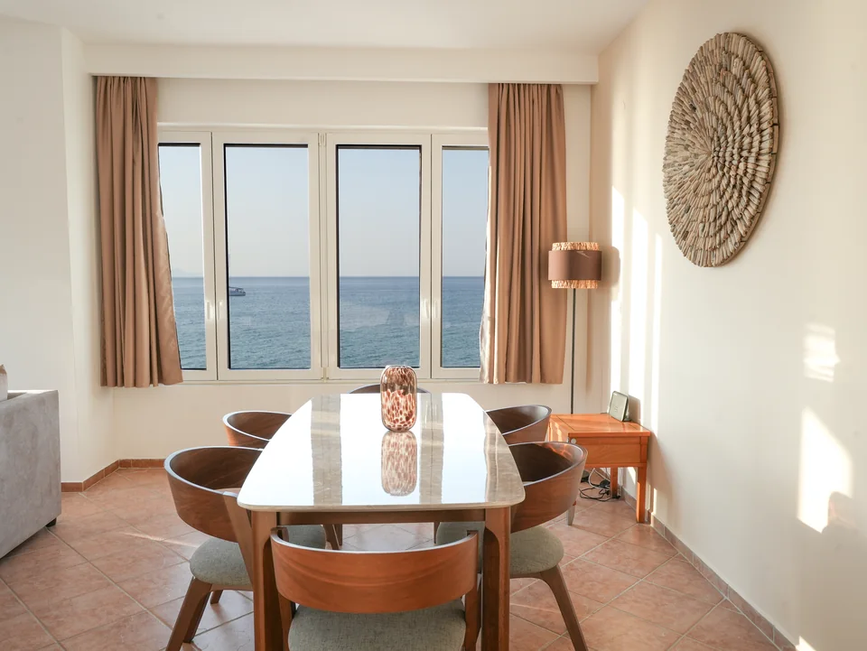 Dining table for four beside floor-to-ceiling windows over the sea