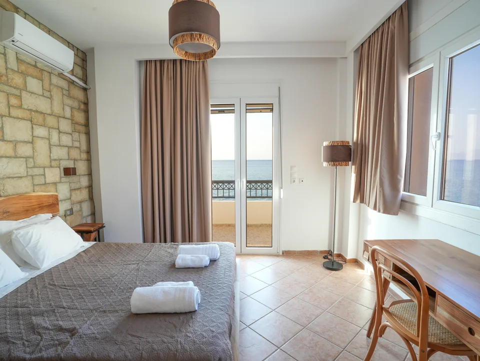 Double bedroom with balcony doors and folded towels on the bed
