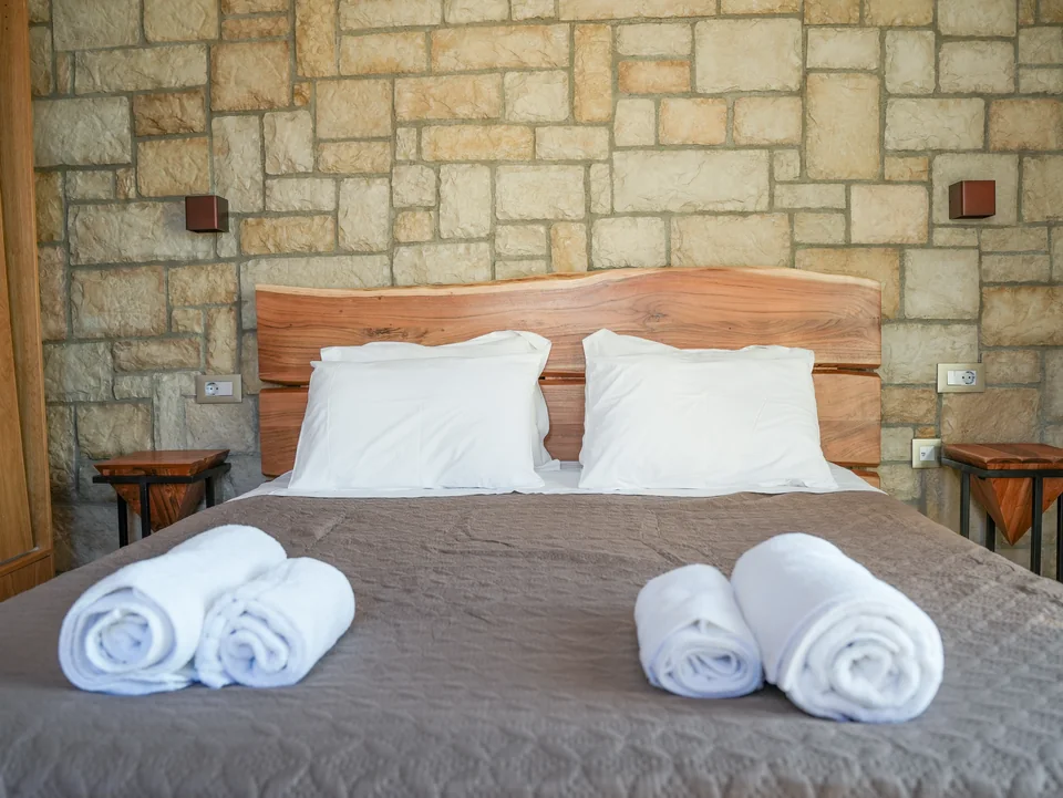 Double bed against a stone feature wall with bedside tables