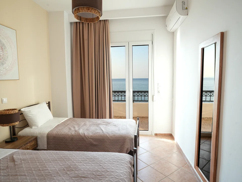 Twin beds beside the balcony with the Aegean beyond
