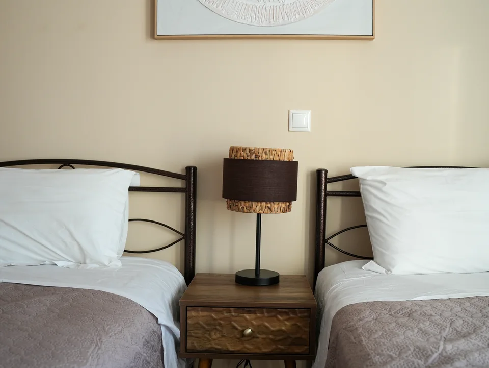 Twin beds with woven lampshades and framed artwork
