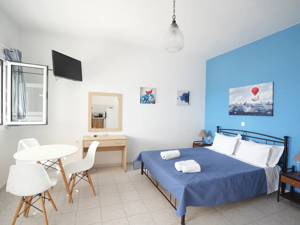 Studio interior with double bed, desk and dining chairs