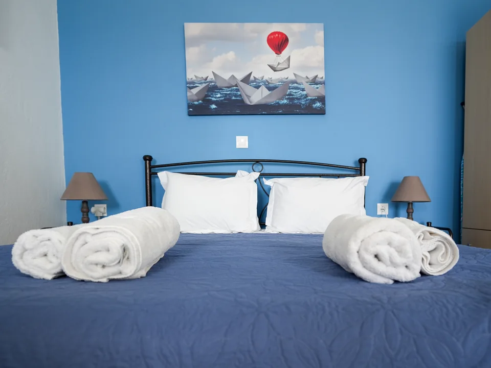 Double bed with towels against the blue wall